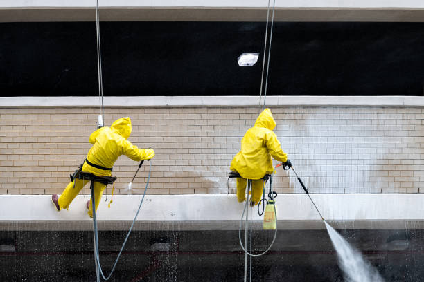 Reston, USA - April 11, 2018: Town center building parking garage architecture with men construction workers on scaffold hanging cleaning wall spraying water