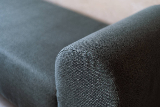 Selective focus on upholstery of new couch. Cleaning service, repair and restoration furniture concept. Close up view of green textile on comfortable sofa or armchair in apartment